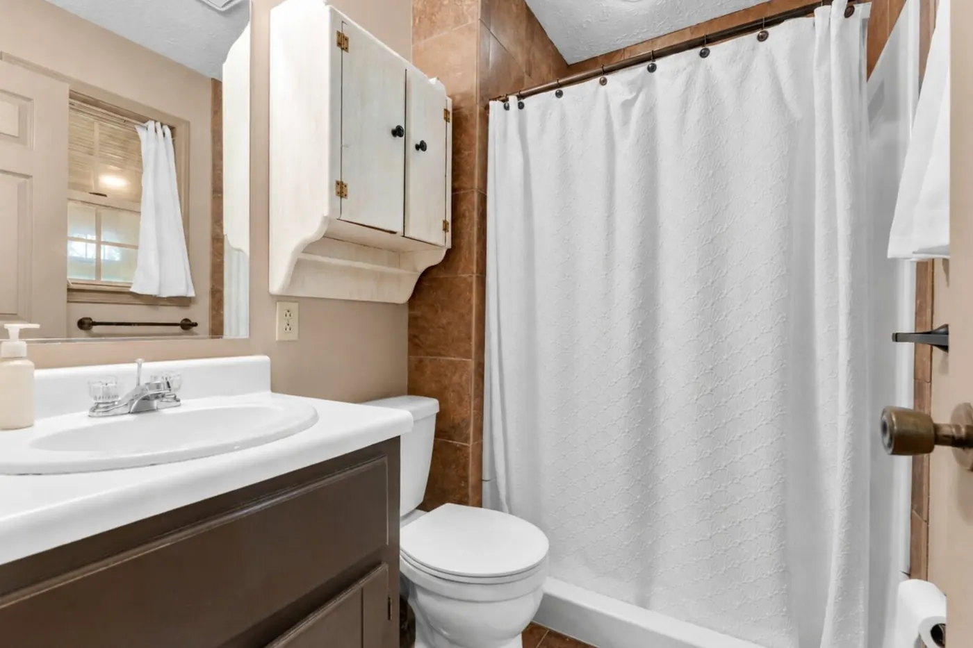A full bath with a vanity, a mirror and a tub shower