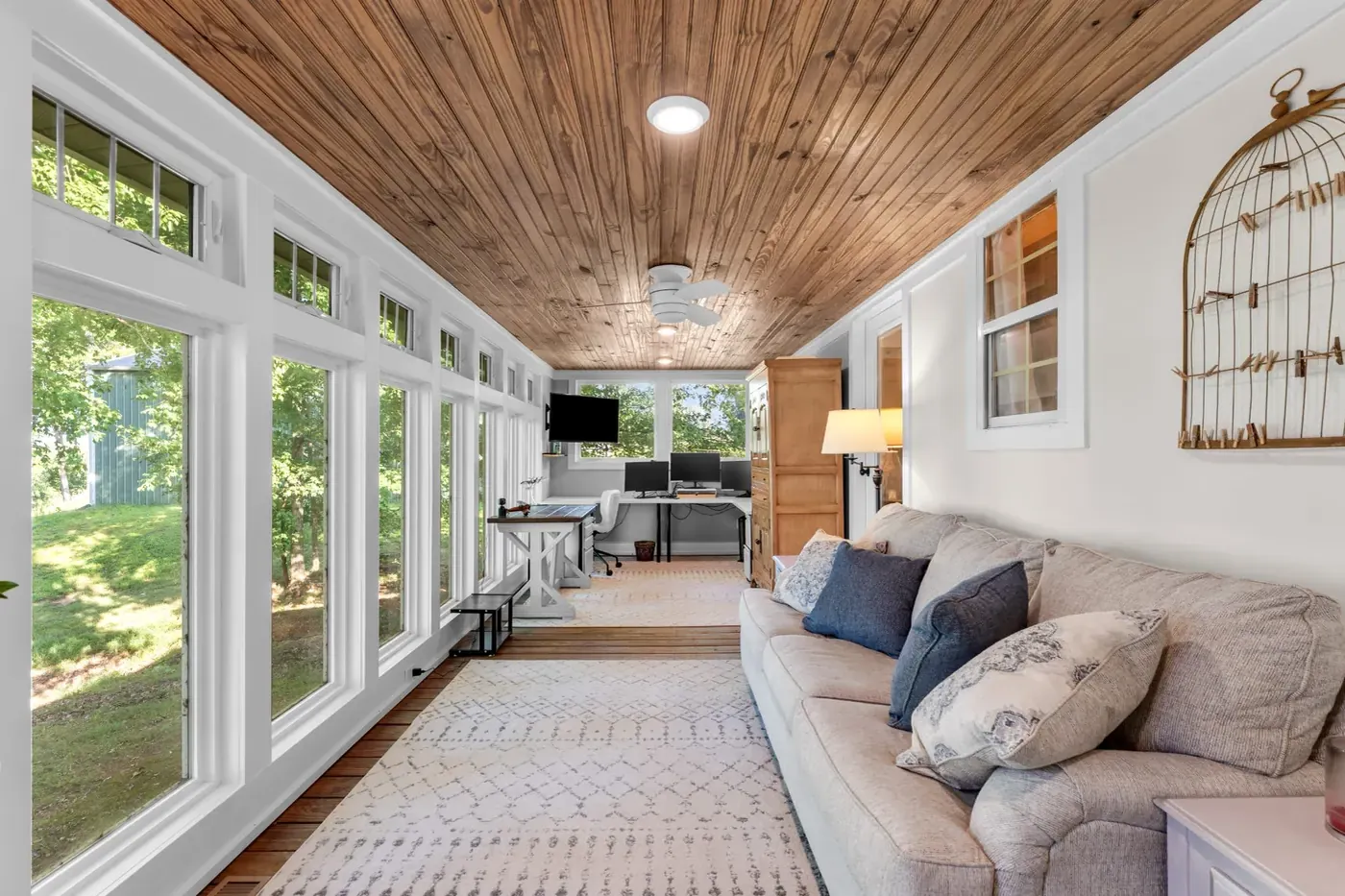 Long sunroom with a wood plank ceiling and windows down one side