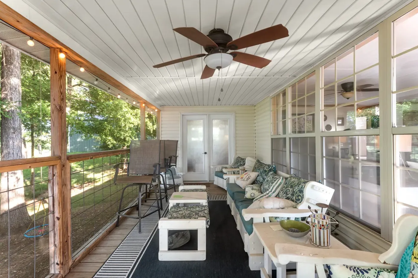 Screened porch with a ceiling fan and seating, looking into the trees