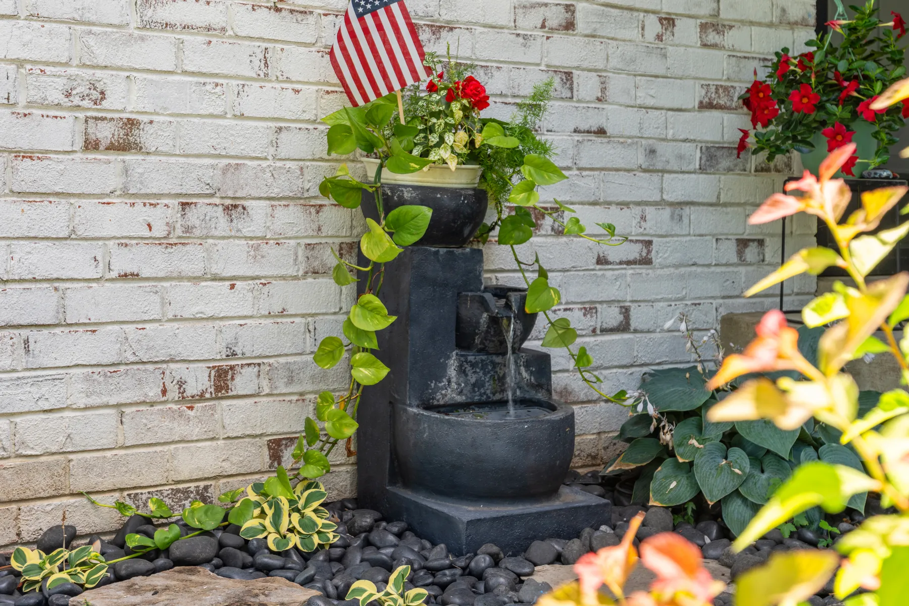 Whitewashed brick wall with a fountain and climbing flowers