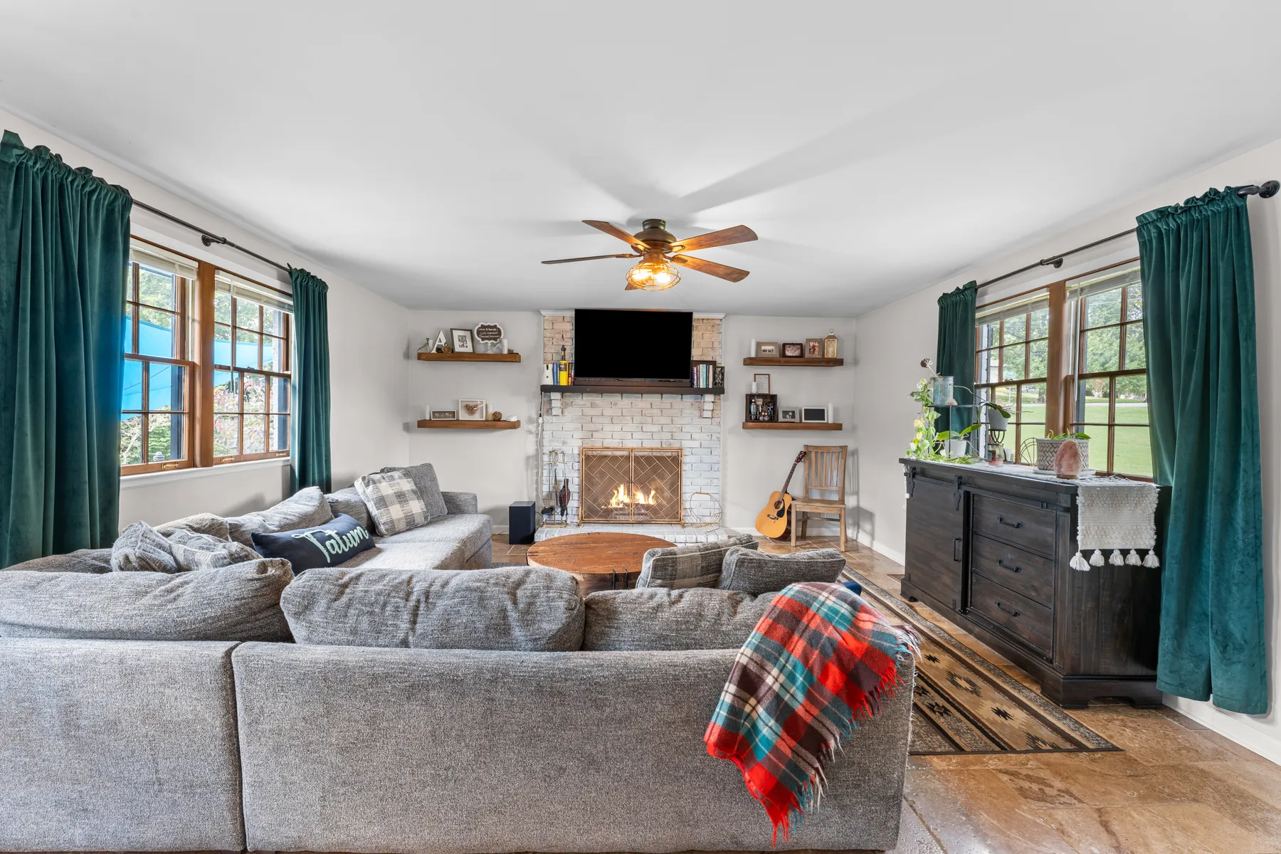 Open great room with a stone fireplace and sectional seating