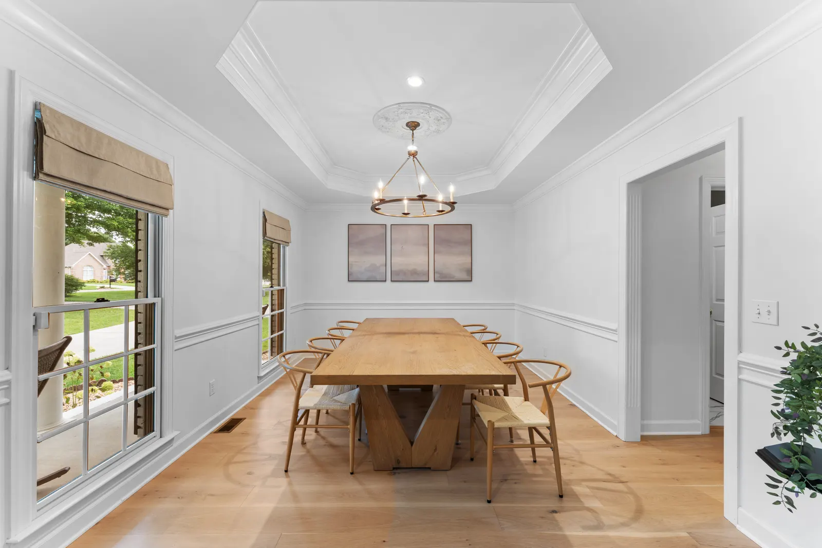 Formal dining room beneath a tray ceiling and chandelier