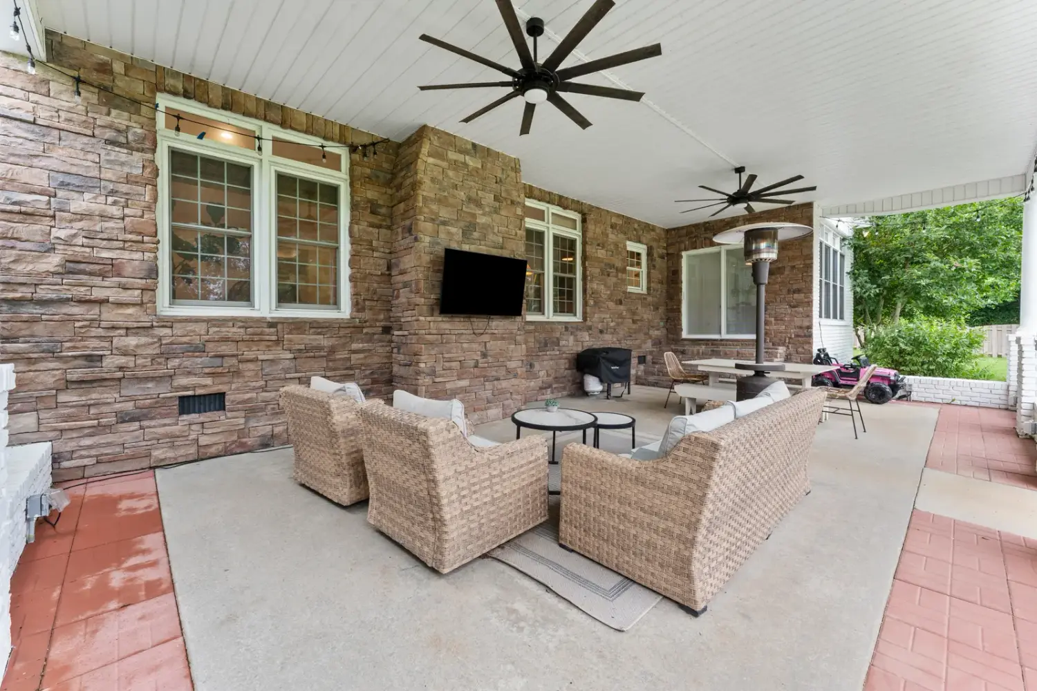 Brick-floored covered porch with a fireplace and lounge seating