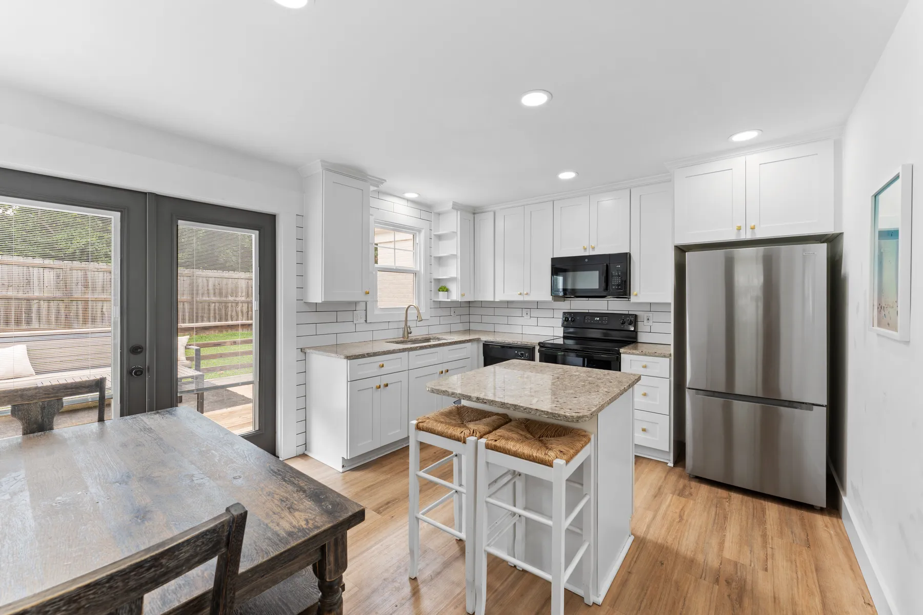 White kitchen with island, granite, and stainless appliances