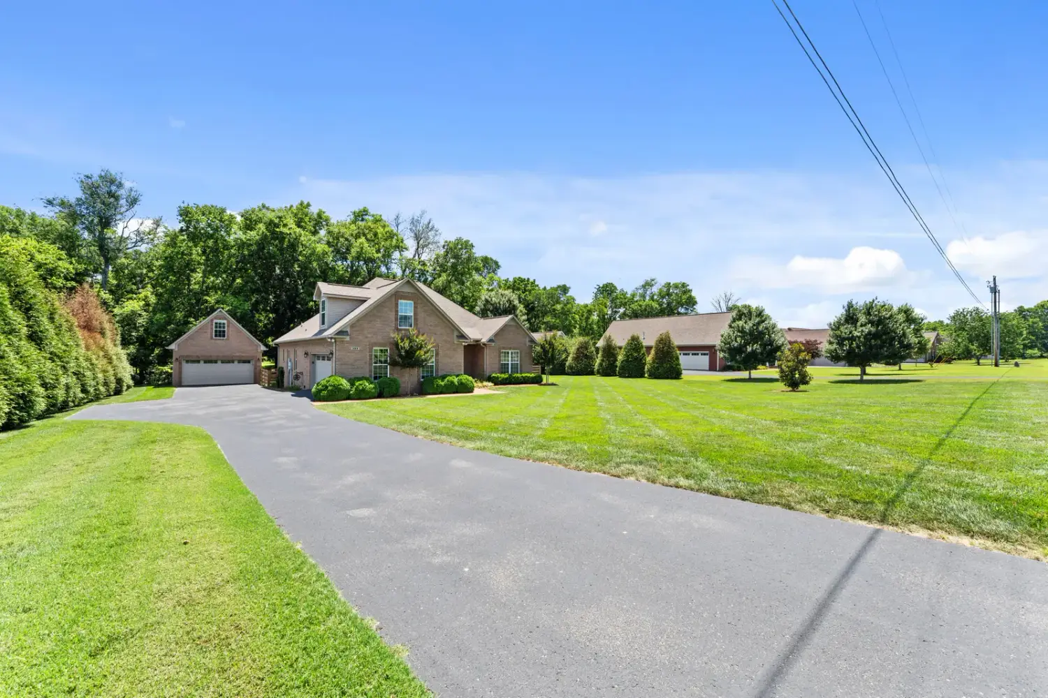 Long driveway approach to the brick estate across a striped lawn