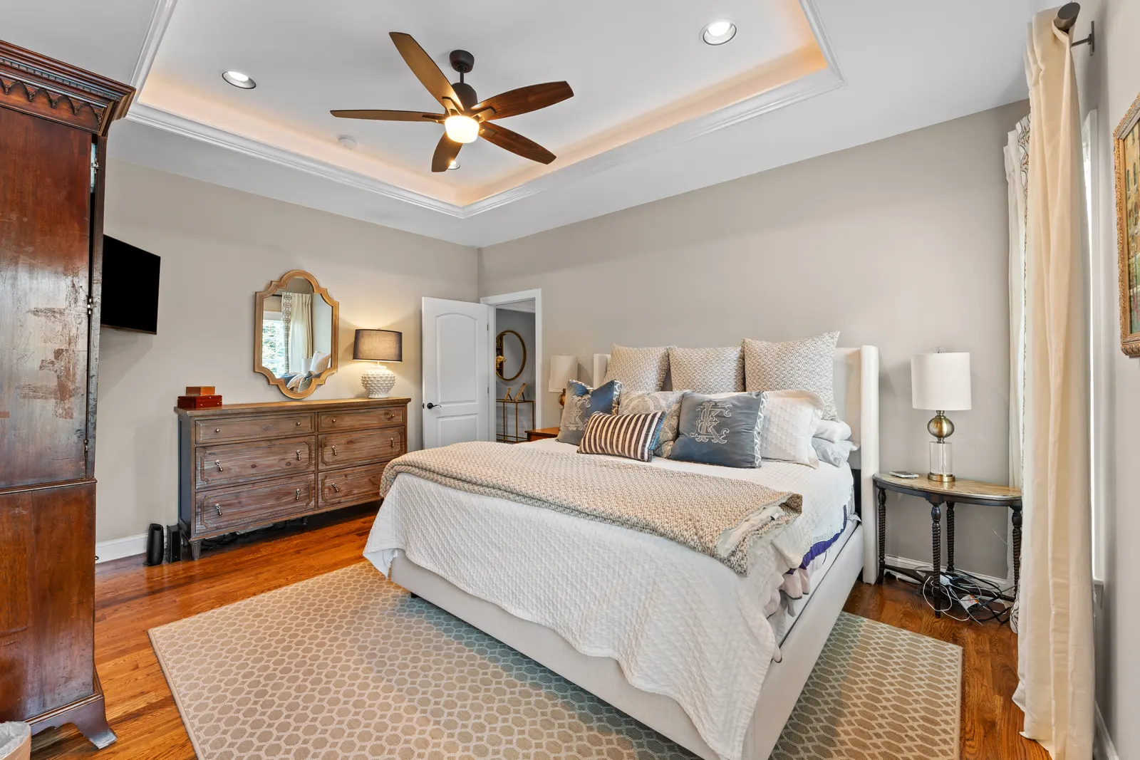 Primary suite with a tray ceiling and hardwood floors
